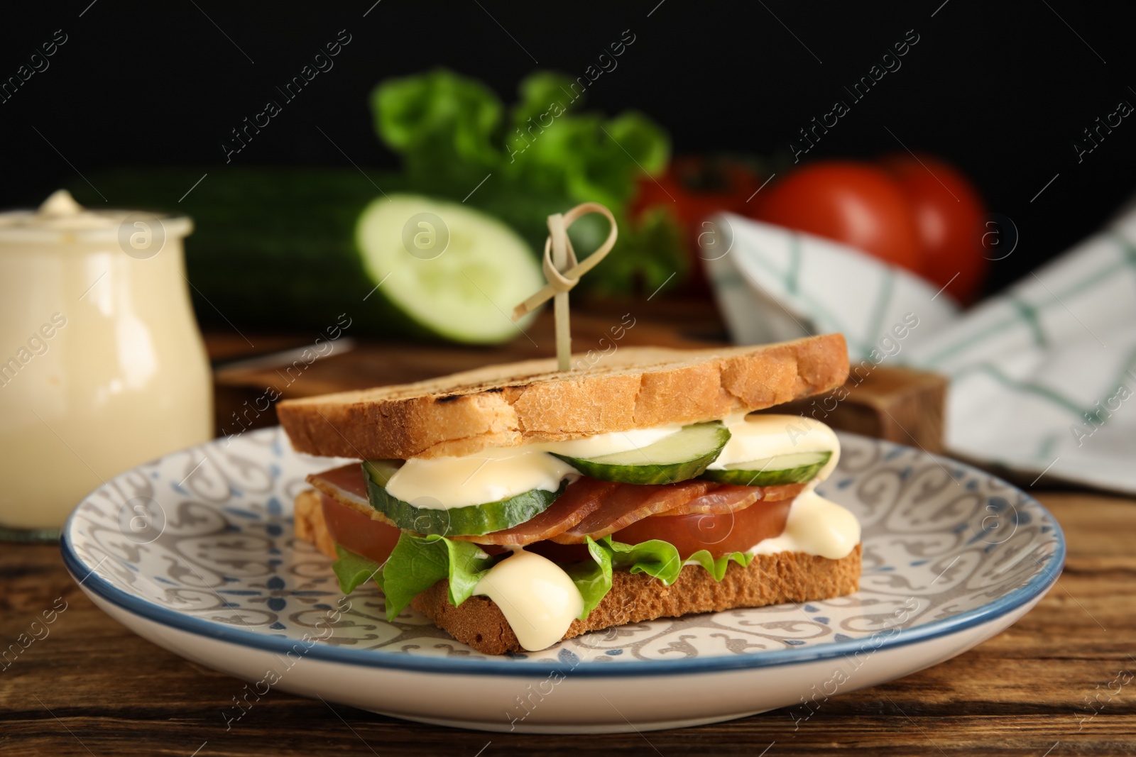 Photo of Delicious sandwich with vegetables, ham and mayonnaise served on wooden table