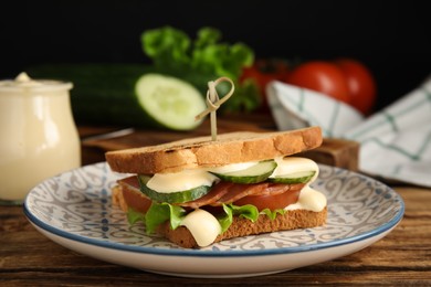 Delicious sandwich with vegetables, ham and mayonnaise served on wooden table