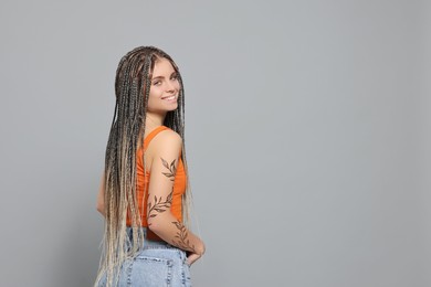 Image of Young woman with beautiful floral tattoo on light grey background, space for text