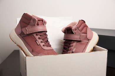 Photo of Pair of stylish kid's sneakers and box on table