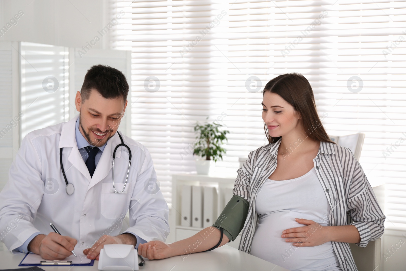 Photo of Doctor measuring blood pressure of pregnant woman in clinic