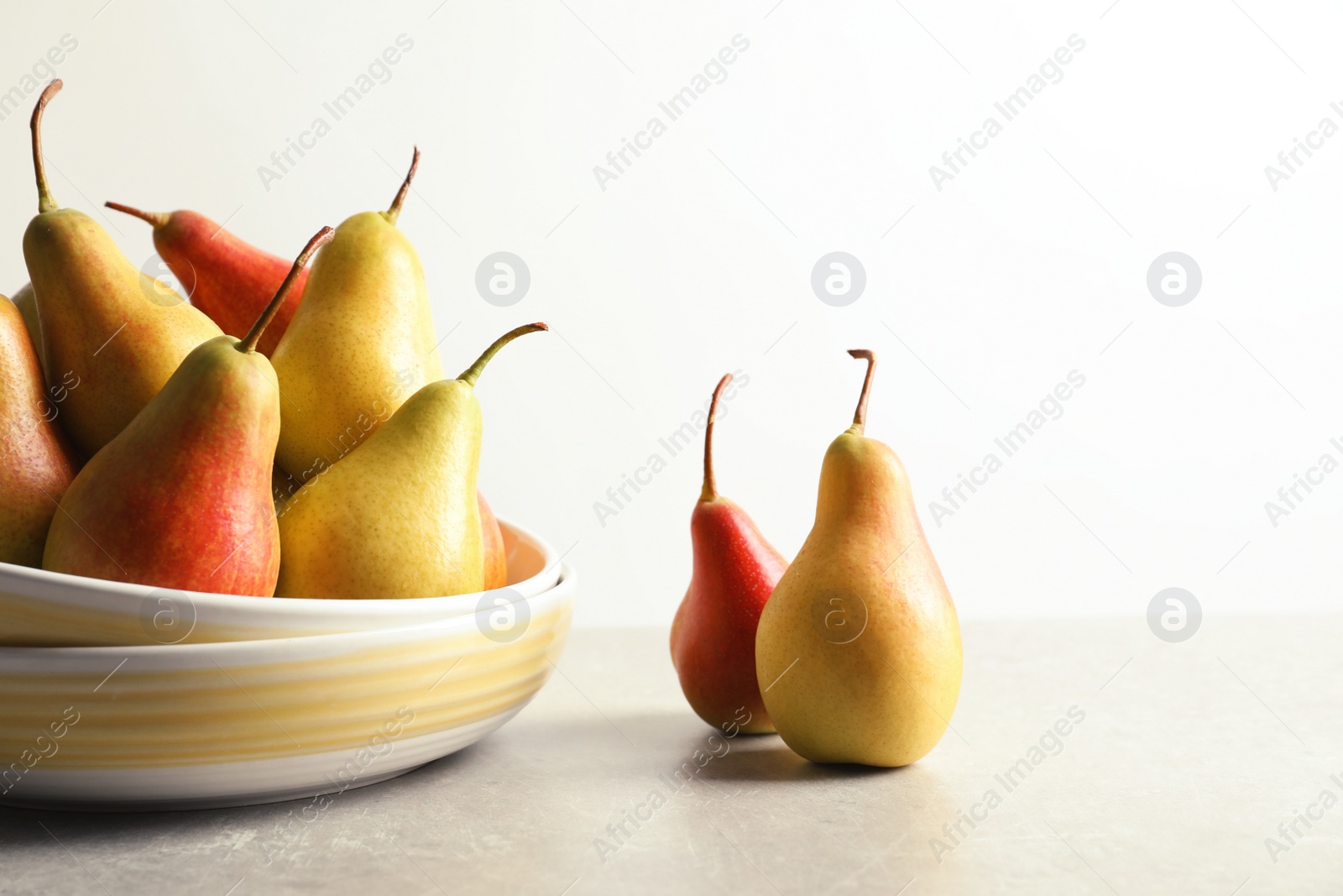 Photo of Plate with ripe pears on table against light background. Space for text