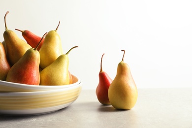 Photo of Plate with ripe pears on table against light background. Space for text