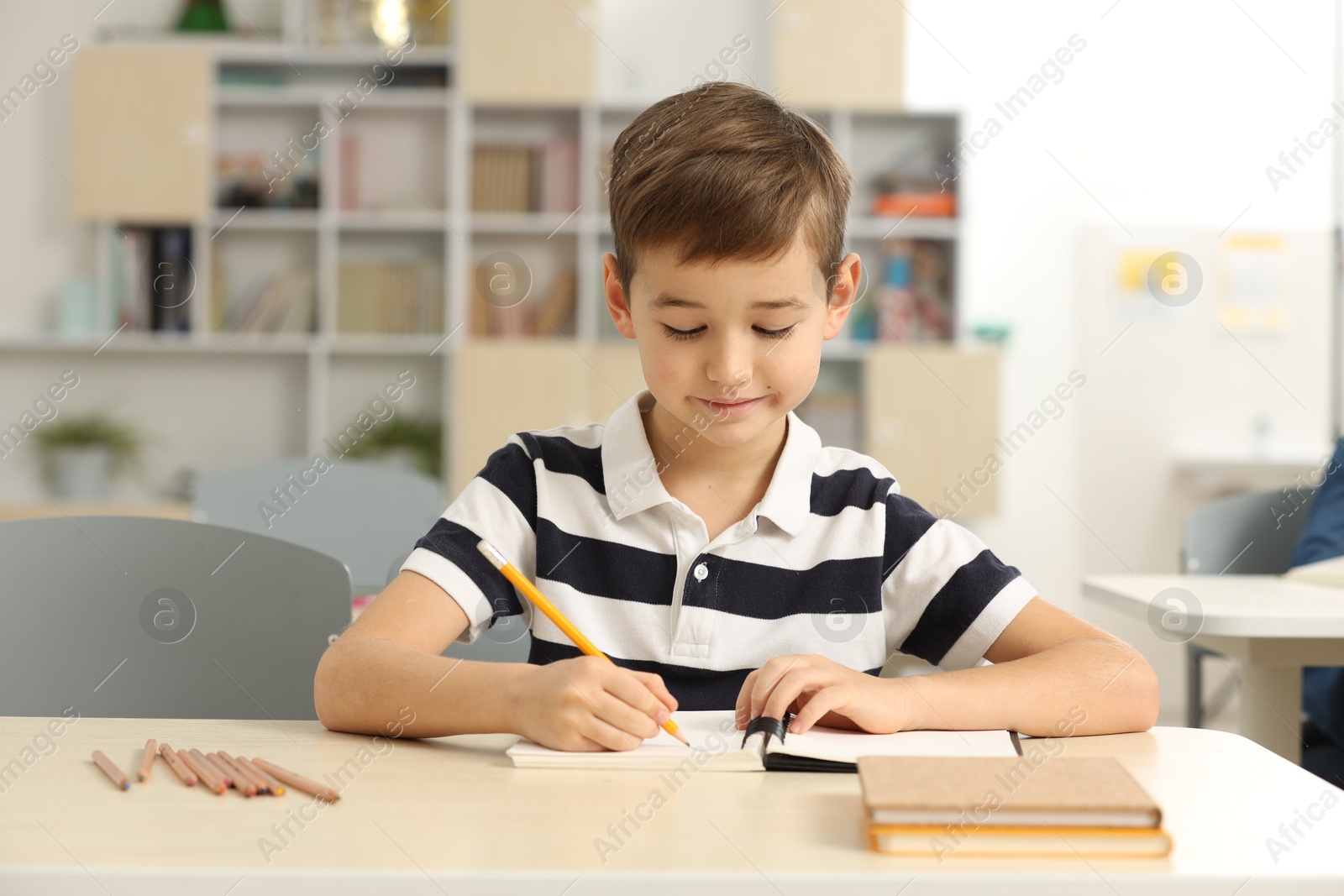 Photo of Portrait of cute little boy studying in classroom at school