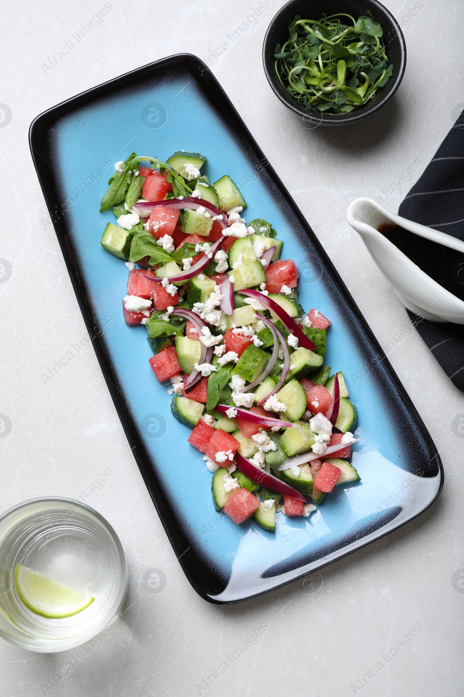 Photo of Delicious salad with watermelon, vegetables and feta cheese served on light table, flat lay