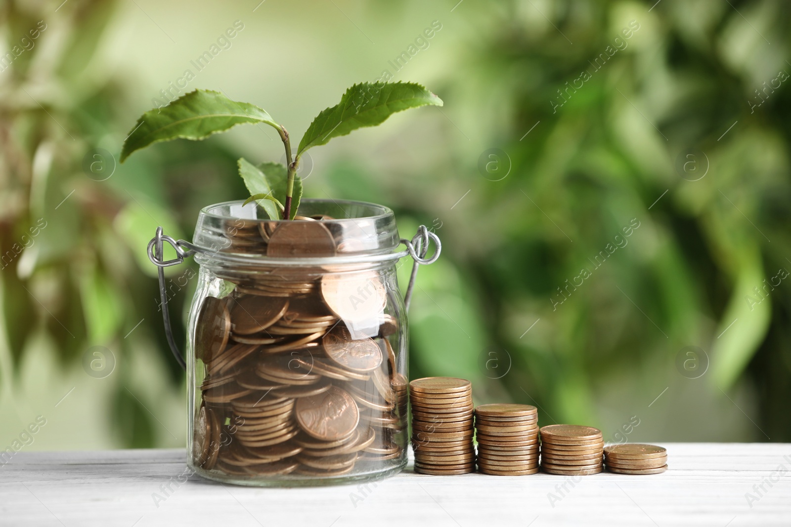 Photo of Coins and green sprout on white wooden table against blurred background. Money savings