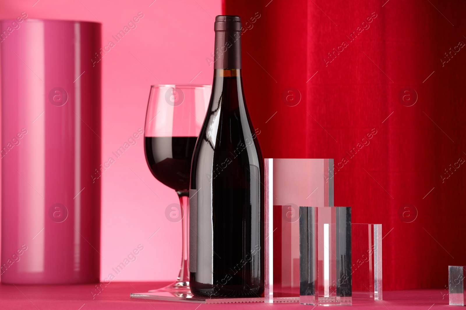 Photo of Stylish presentation of delicious red wine in bottle and glass on color background