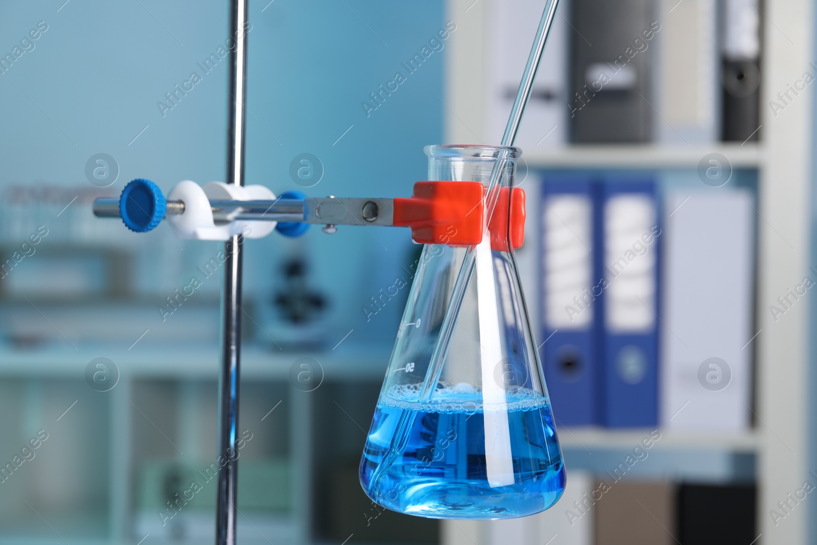 Photo of Laboratory analysis. Glass flask with blue liquid on stand indoors, closeup