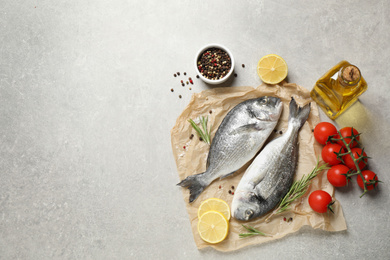 Photo of Flat lay composition with raw dorada fish on light grey table, space for text