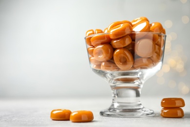Photo of Dessert bowl filled with tasty candies on light table. Space for text