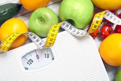 Scales, measuring tape and healthy food on wooden background, closeup. Weight loss