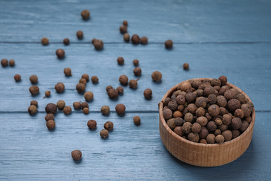 Black peppercorns in bowl on blue wooden table