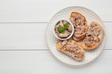 Photo of Tasty sandwiches with cod liver and parsley on white wooden table, top view. Space for text