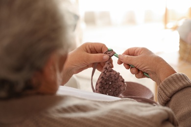 Photo of Elderly woman crocheting at home, closeup. Creative hobby