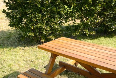 Photo of Empty wooden picnic table with bench in park on sunny day