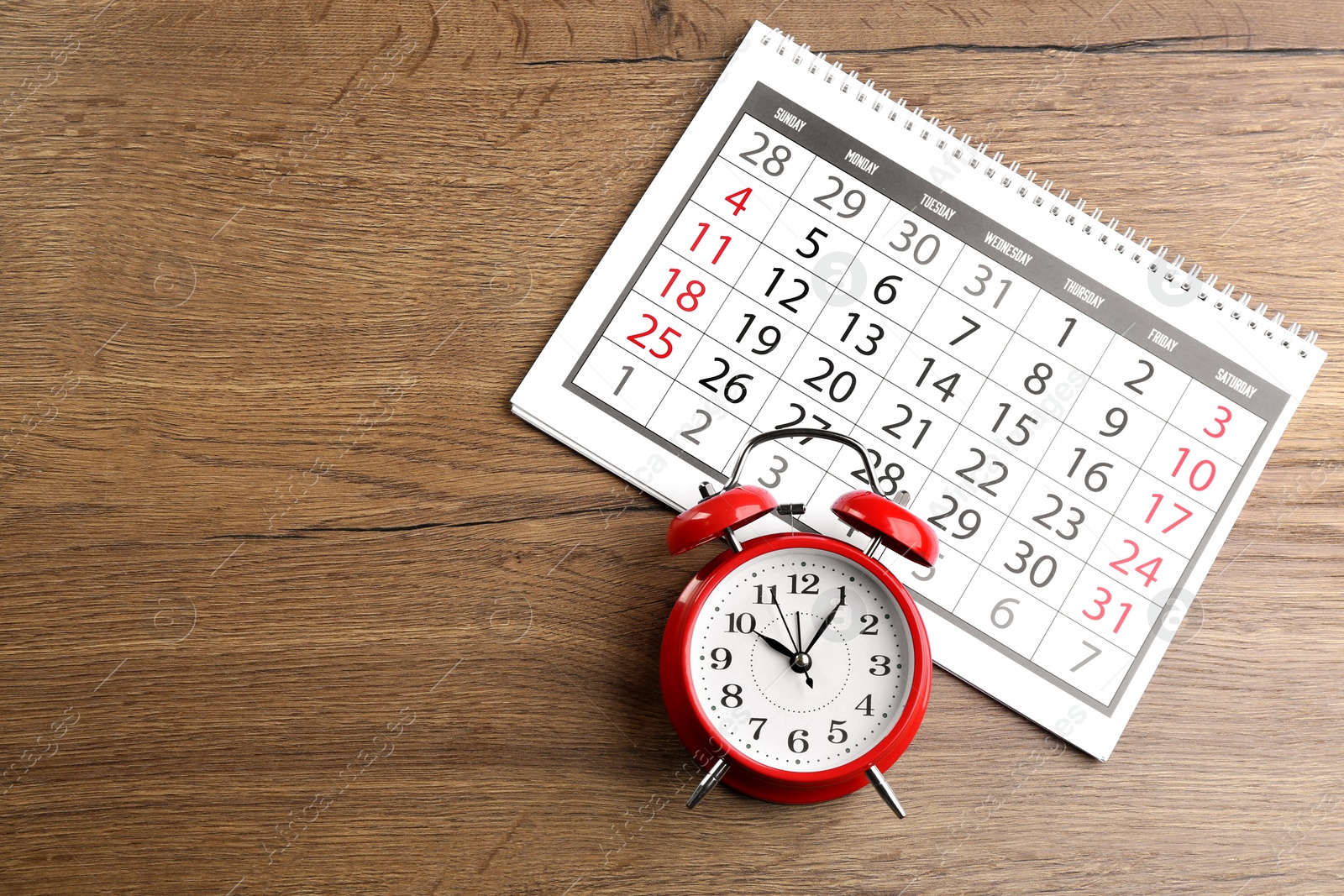 Photo of Calendar and alarm clock on wooden table, flat lay. Space for text