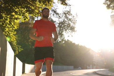 Photo of Happy man running outdoors on sunny day, low angle view. Space for text