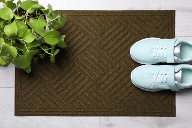 Photo of New clean door mat, shoes and houseplant on floor, flat lay