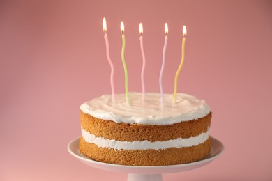 Photo of Tasty cake with colorful candles on pink background, closeup