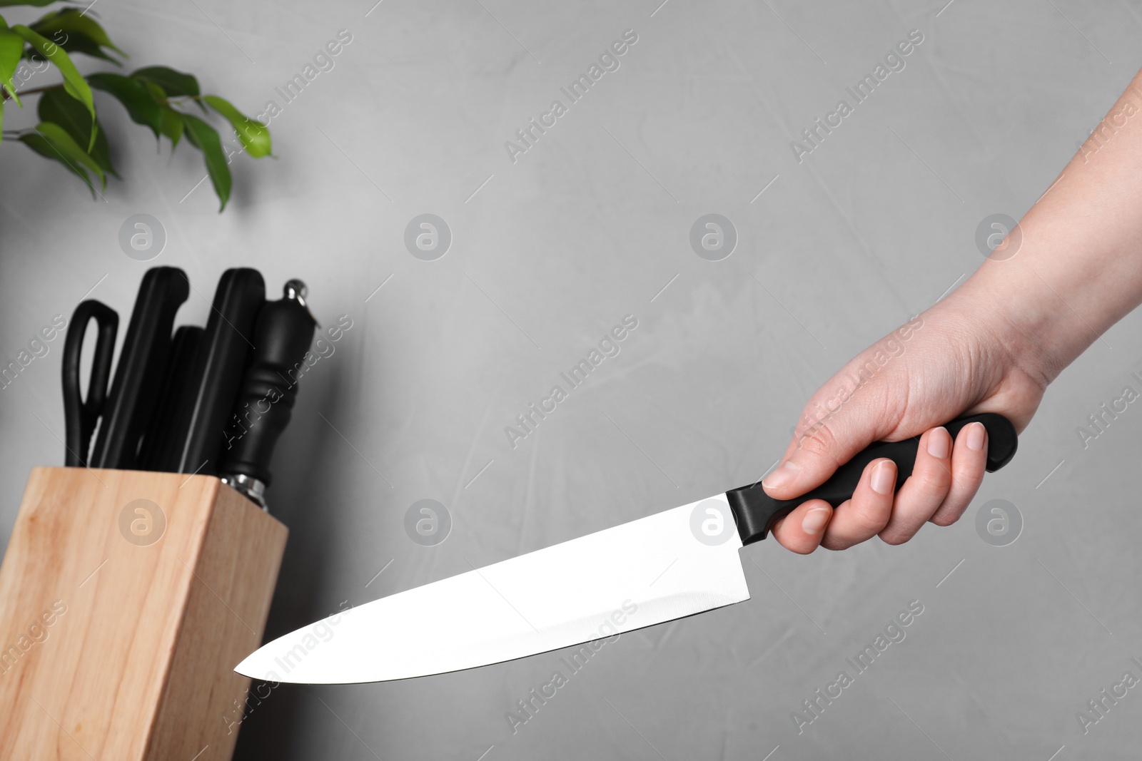 Photo of Woman holding chef knife on grey background, closeup. Clean dishes