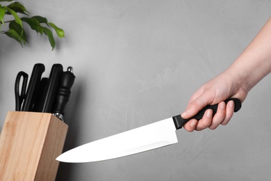 Photo of Woman holding chef knife on grey background, closeup. Clean dishes