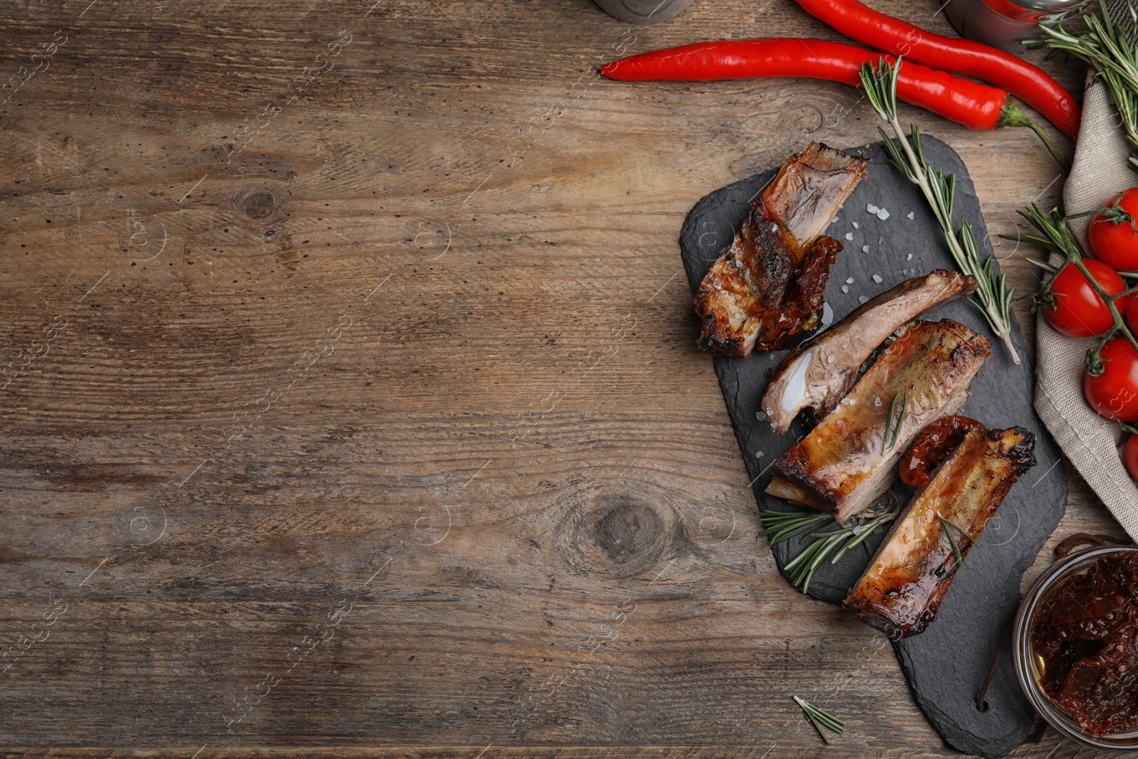 Photo of Tasty grilled ribs with rosemary on wooden table, flat lay. Space for text