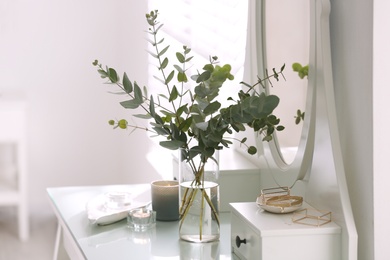 Beautiful eucalyptus branches on dressing table in room. Interior design