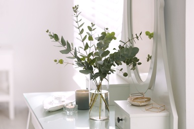 Photo of Beautiful eucalyptus branches on dressing table in room. Interior design