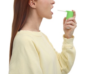 Young woman using throat spray on white background, closeup