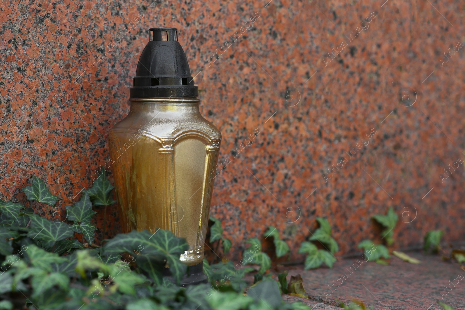 Photo of Grave lantern and ivy near tombstone in cemetery, space for text