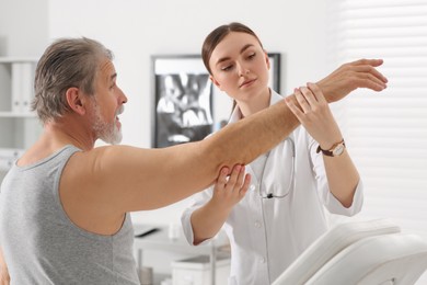 Female orthopedist examining patient's arm in clinic