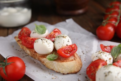 Delicious sandwich with mozzarella, fresh tomato and basil on parchment