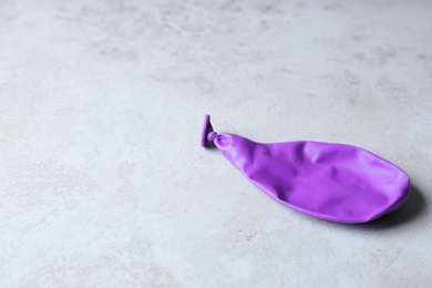 Photo of Purple deflated balloon on grey background, space for text