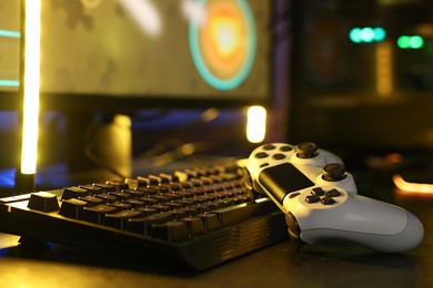 Playing video games. Computer keyboard and wireless controller on table, closeup