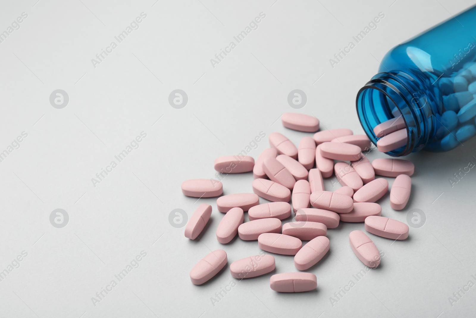 Photo of Vitamin pills and bottle on grey background, closeup. Space for text