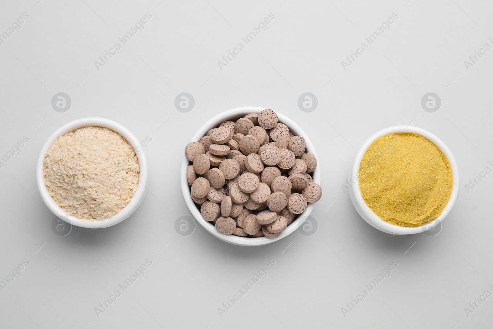 Photo of Bowls with different types of brewer`s yeast on light grey background, top view