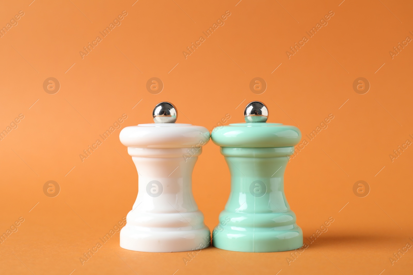 Photo of Salt and pepper shakers on orange background, closeup