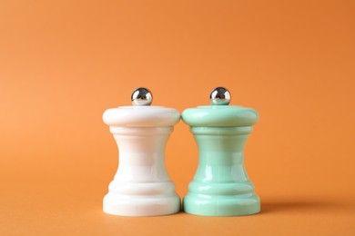 Photo of Salt and pepper shakers on orange background, closeup