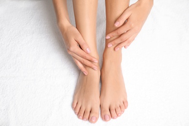 Woman touching her smooth feet on white towel, closeup. Spa treatment