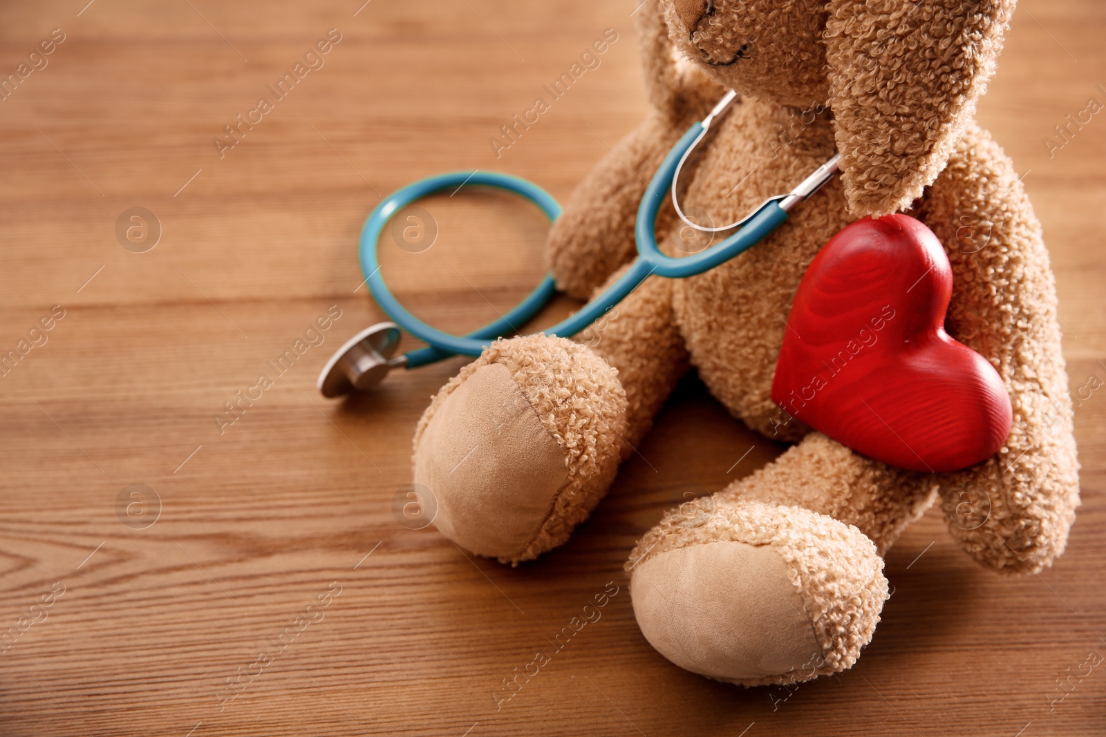 Photo of Toy bunny, stethoscope and heart on wooden background, closeup. Children's doctor