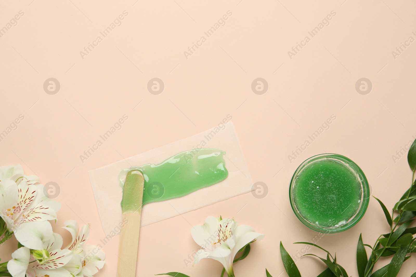 Photo of Wax with spatula, paper and flowers on beige background, flat lay. Space for text