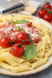 Tasty pasta with tomato sauce, cheese and basil on grey table, closeup