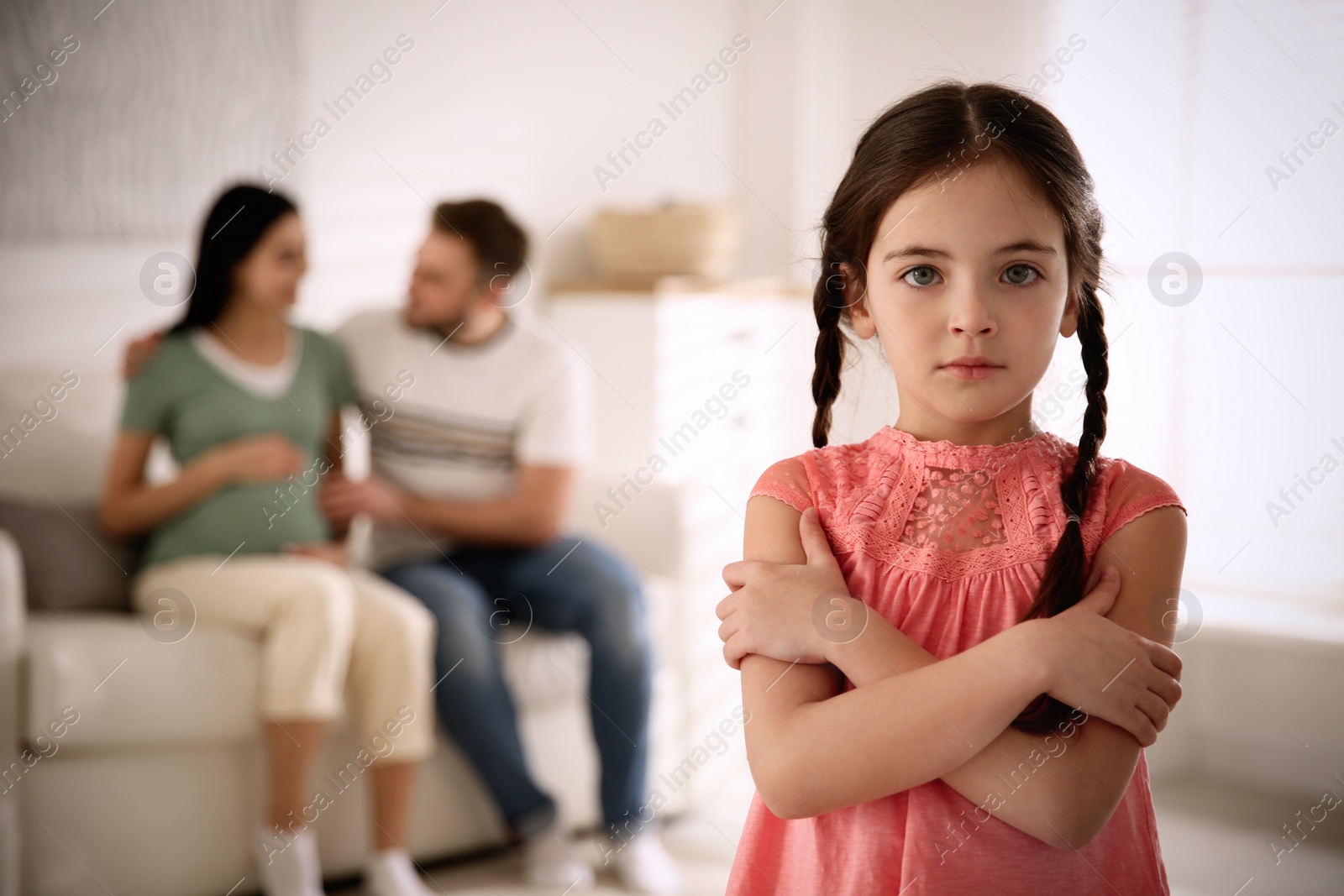 Photo of Unhappy little girl and her father with pregnant mother at home. Feeling jealous towards unborn sibling