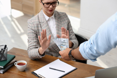 Photo of Businesswoman refuses to take bribe money at table in office