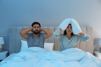 Photo of Young couple suffering from noisy neighbours in bed at home