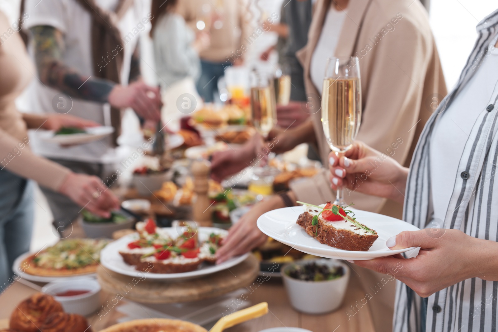 Photo of Woman with glass of champagne and sandwich near brunch buffet indoors, closeup. Space for text