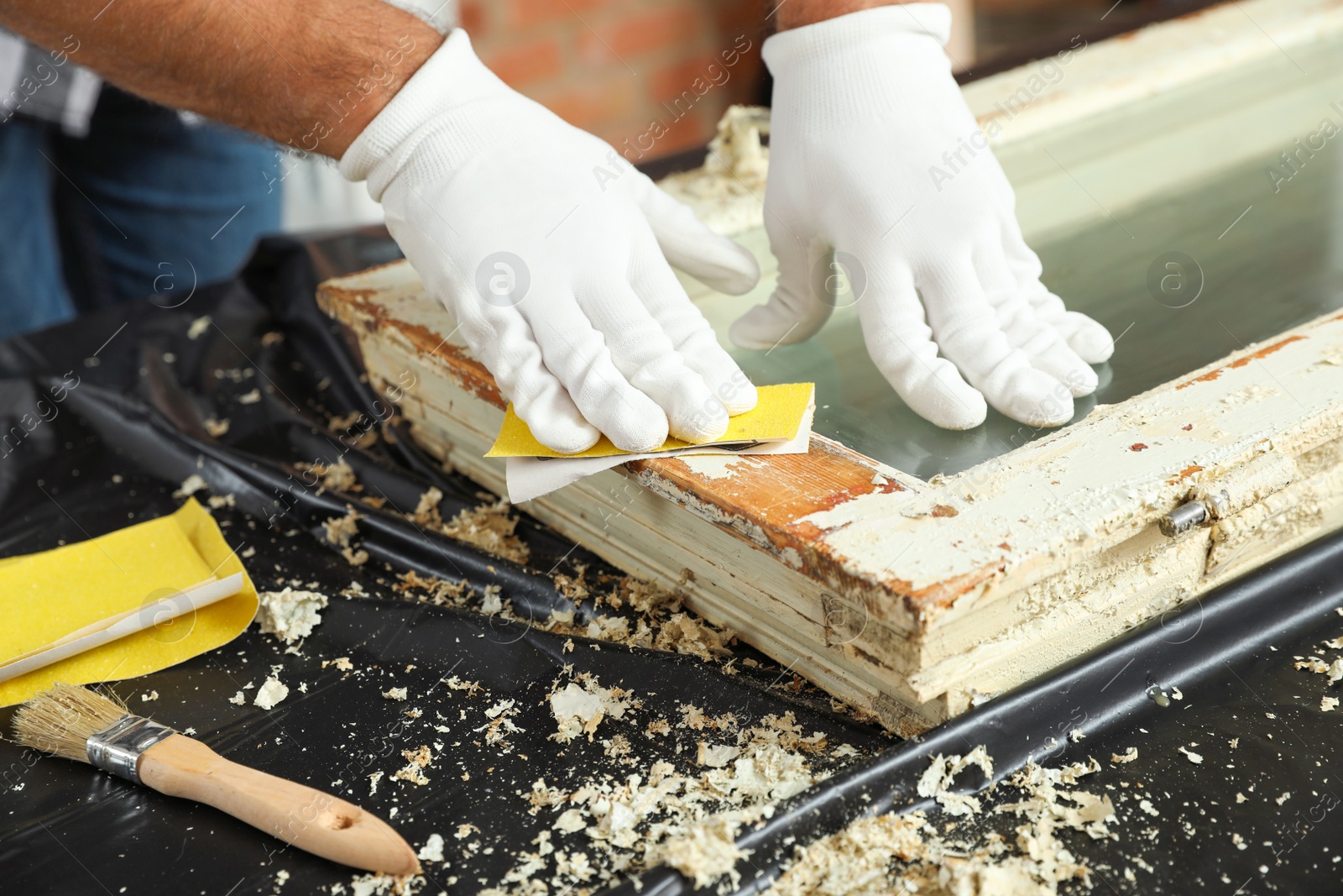 Photo of Man repairing old damaged window at table indoors, closeup