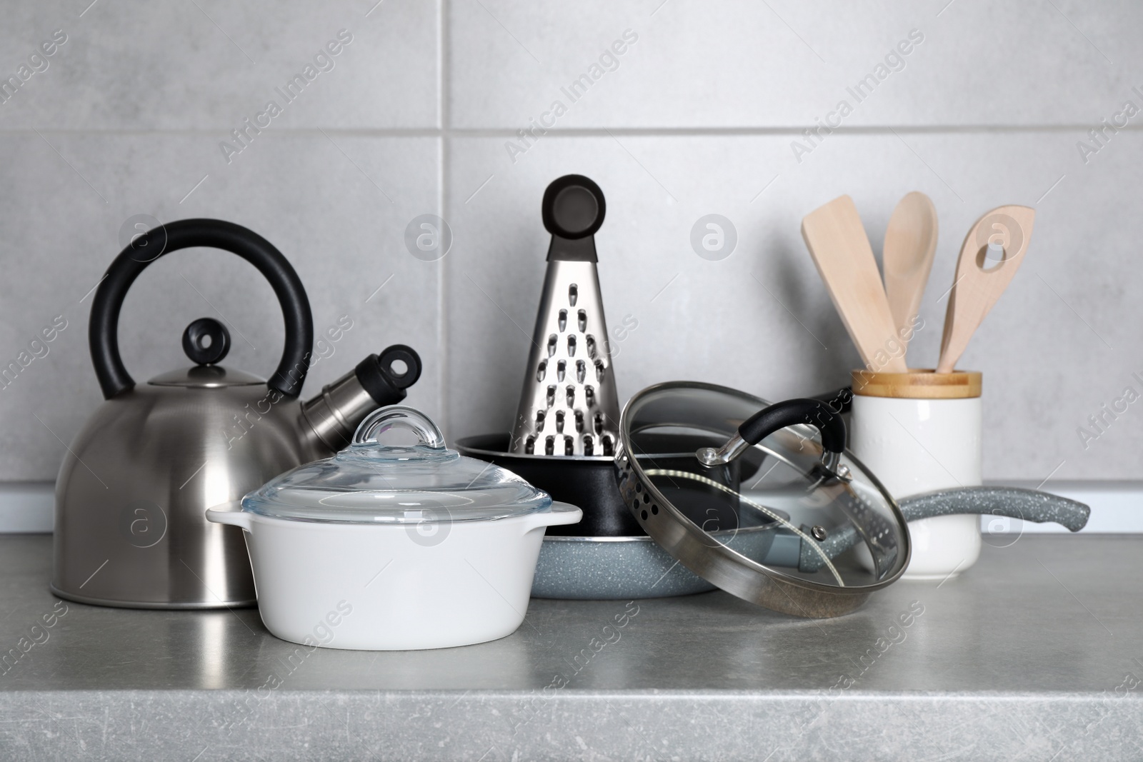 Photo of Set of cooking utensils and cookware on grey countertop