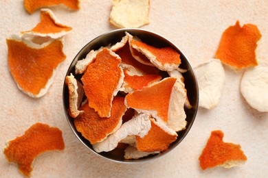 Photo of Dry orange peels with bowl on beige table, flat lay