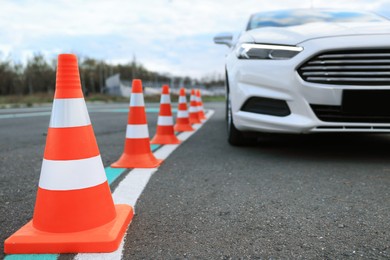 Photo of Modern car on test track with traffic cones, closeup. Driving school